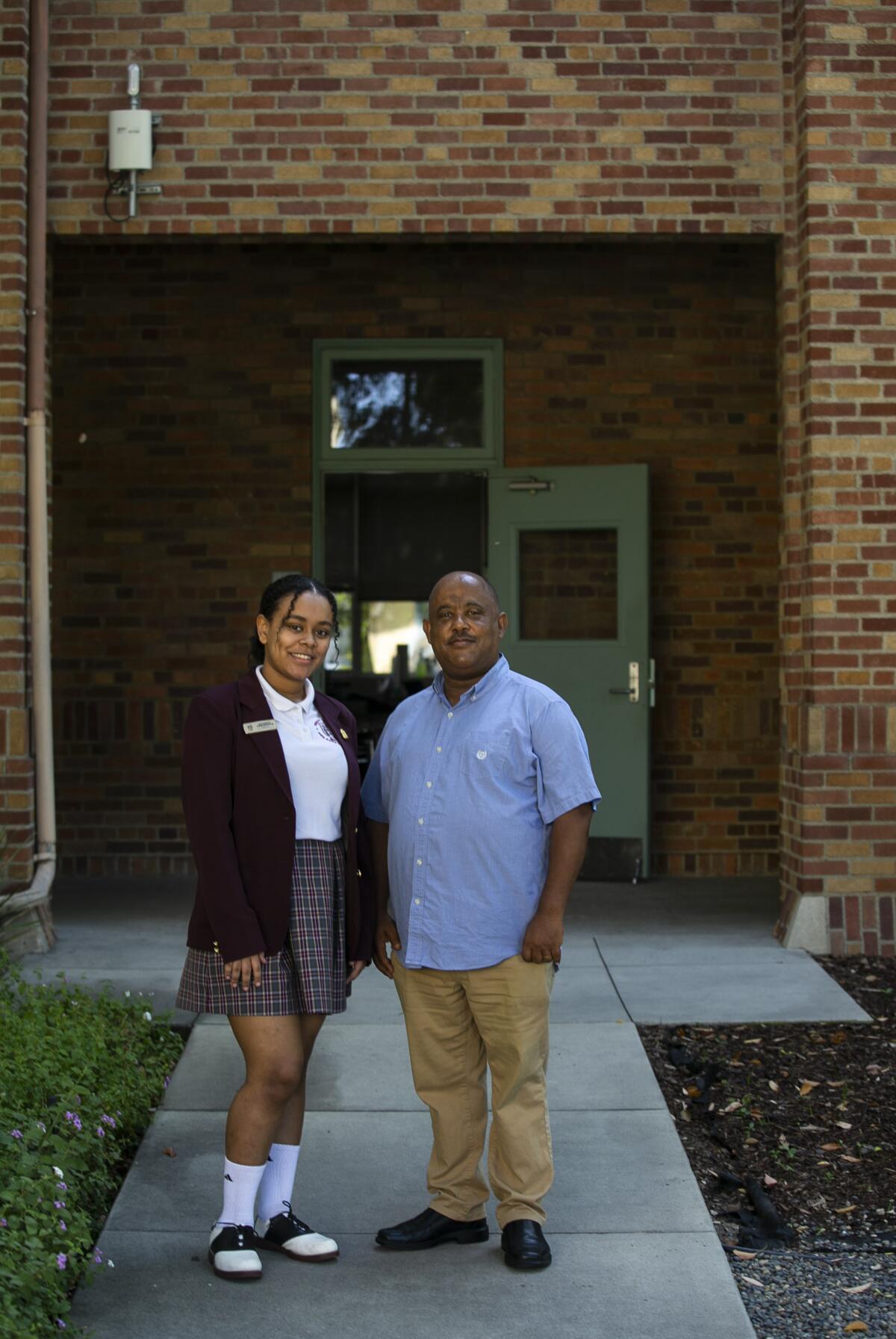 A father and daughter pose outside a high school