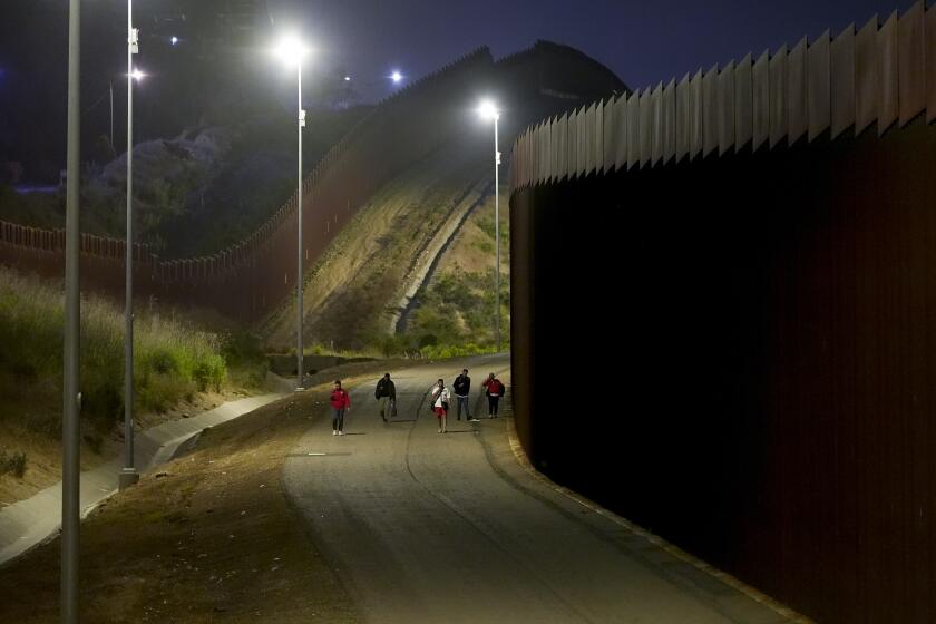 Migrantes jordanos caminan a lo largo de los muros fronterizos que separan a la ciudad mexicana de Tijuana de San Diego, con el fin de solicitar asilo ante las autoridades estadounidenses, el martes 7 de mayo de 2024, en San Diego. (AP Foto/Ryan Sun)
