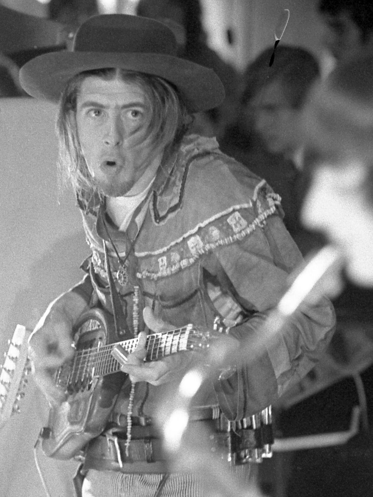 Black and white photo of a man in a cowboy outfit playing guitar