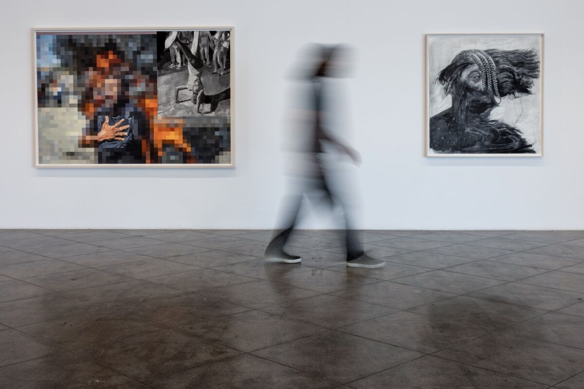 Космо Уайт сфотографирован размытым между двумя своими работами.