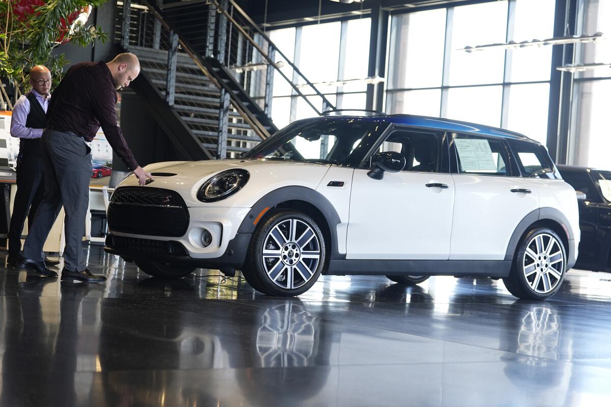 Salesmen examine an unsold 2024 Cooper Clubman S utility vehicle