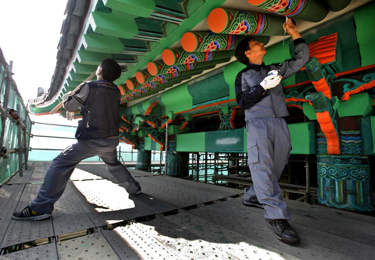A crew of Korean painters works on the Korean Friendship Bell's pagoda.