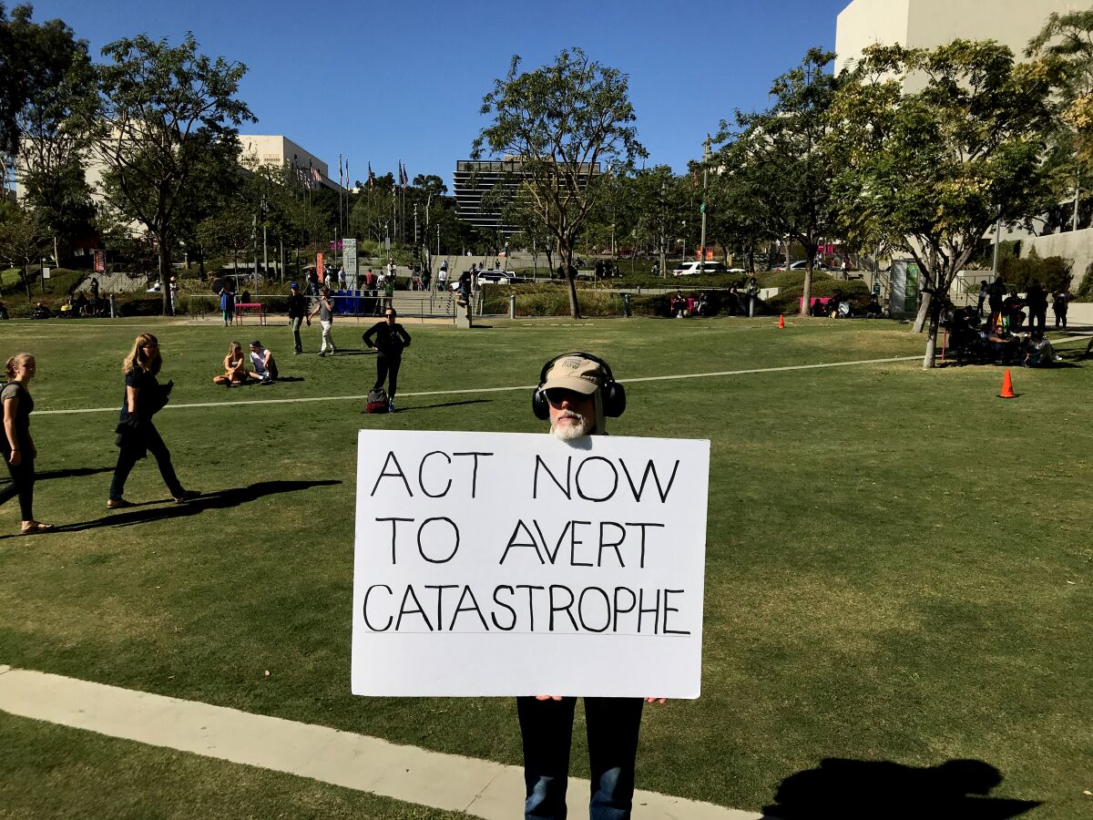 Bob Frang of Santa Monica holds a sign Friday in Grand Park in downtown L.A. before the climate change march.