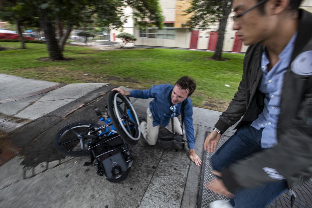 A passerby, right, rushes in to help after David Radcliff took a tumble while crossing a section of broken sidewalk on Jefferson Boulevard in his wheelchair.