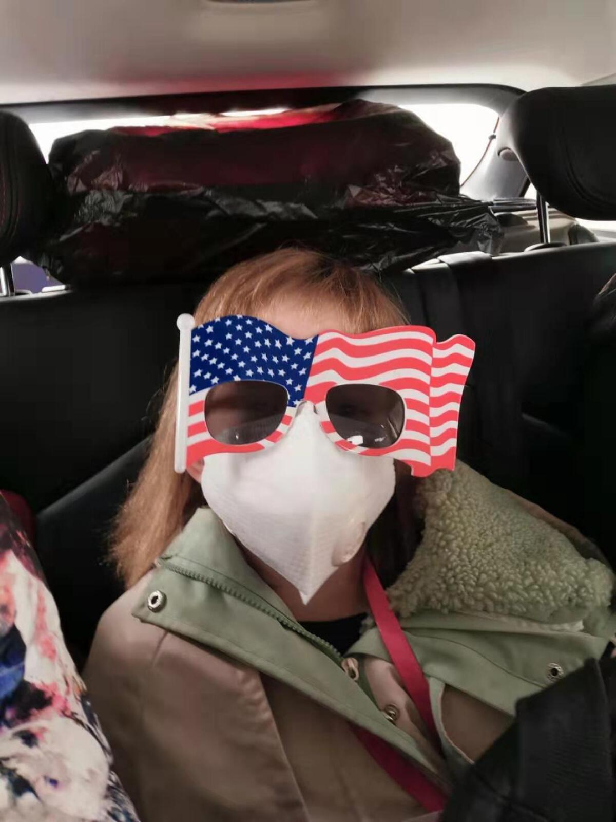An 8-year-old American rides in a car on her way to Wuhan Tianhe International Airport for a U.S. evacuation flight Tuesday.