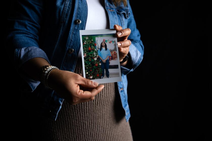 Karen Marquez holding a photo of her husband standing next to a Christmas tree. Marquez's face is not shown.