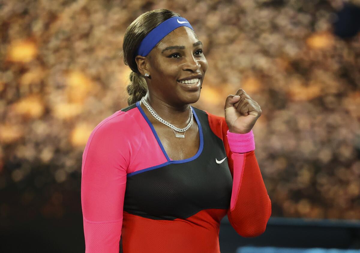 Serena Williams smiles and holds up a fist