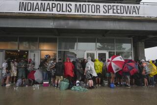 Fanáticos se aglomeran debajo de las grederías mientras la fuerte lluvia y los relámpagos retrasan el inicio de las 500 millas de Indianápolis, en el Indianapolis Motor Speed Way, en Indianápolis, el domingo 26 de mayo de 2024. (AP Foto/Michael Conroy)