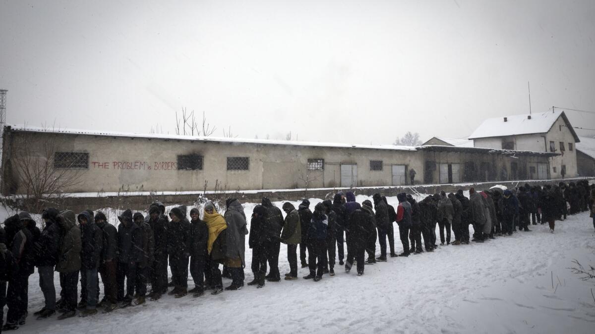 Migrants wait in line to receive free food outside a derelict customs warehouse on Jan. 11, 2017, in Belgrade, Serbia.