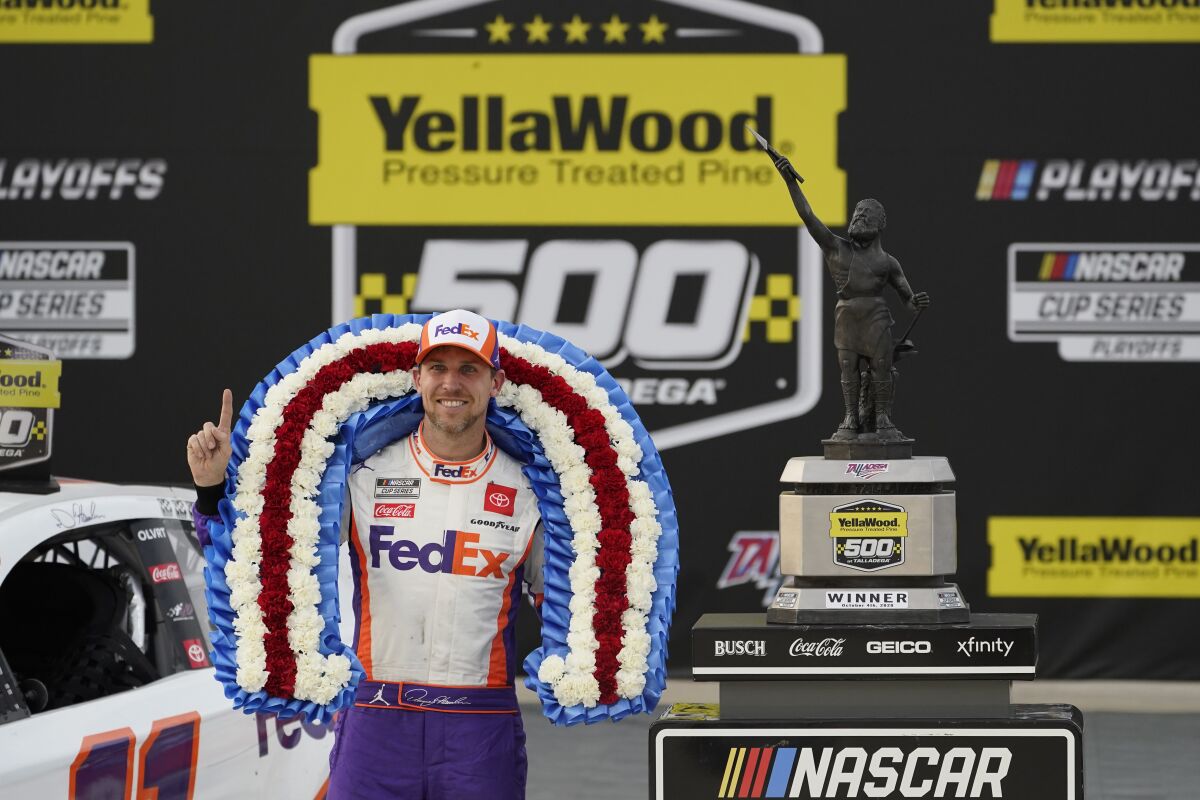 Denny Hamlin poses with the trophy after winning the NASCAR Cup Series auto race.