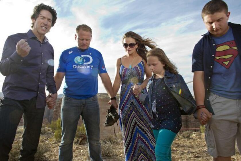 Preacher Joel Osteen, left, leads a prayer with Nik Wallenda, second from left, his wife, Erendira, daughter Evita and son Yanni before Wallenda walked a 2-inch-thick steel cable that took him a quarter-mile over the Little Colorado River Gorge in northeastern Arizona on Sunday.