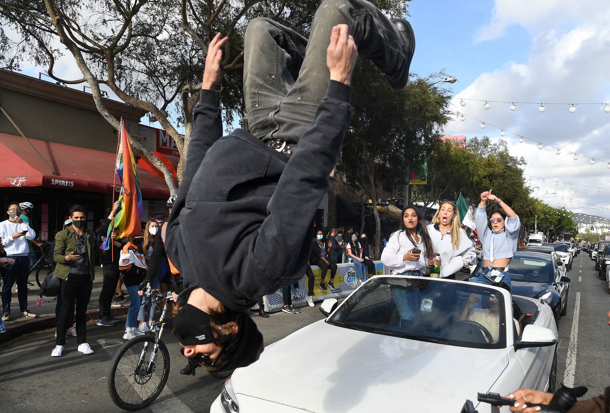 A person does a back flip off the hood of a car in celebration along Santa Monica Boulevard in West Hollywood.