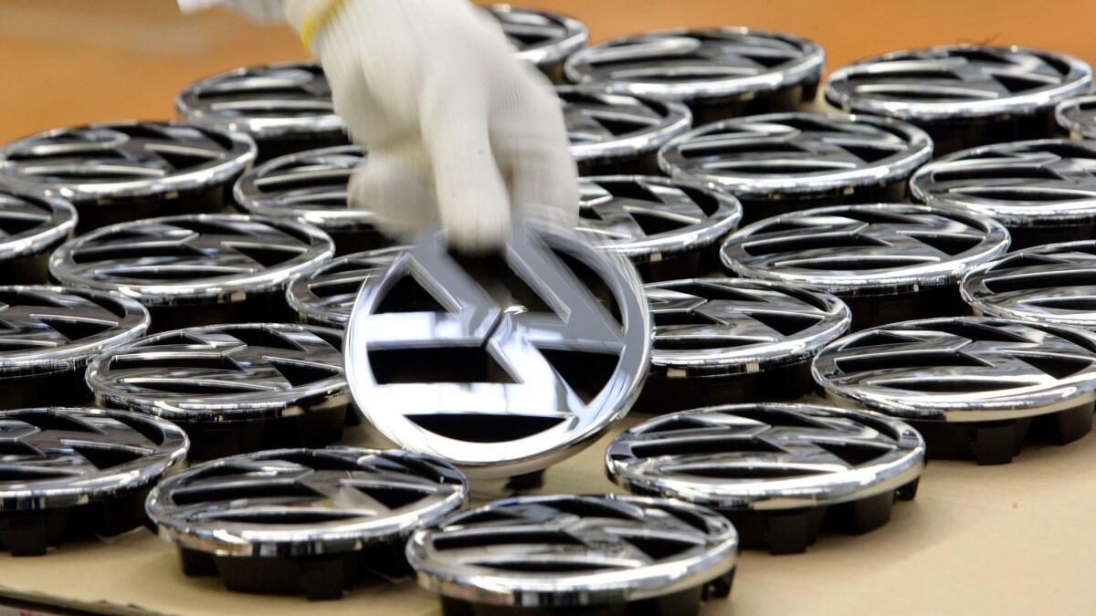 The EPA and the California Air Resources Board had to approve the fix under a $1.2-billion settlement approved by a federal judge this spring. Above, a worker takes a VW-emblem at the Volkswagen factory in Wolfsburg, Germany.