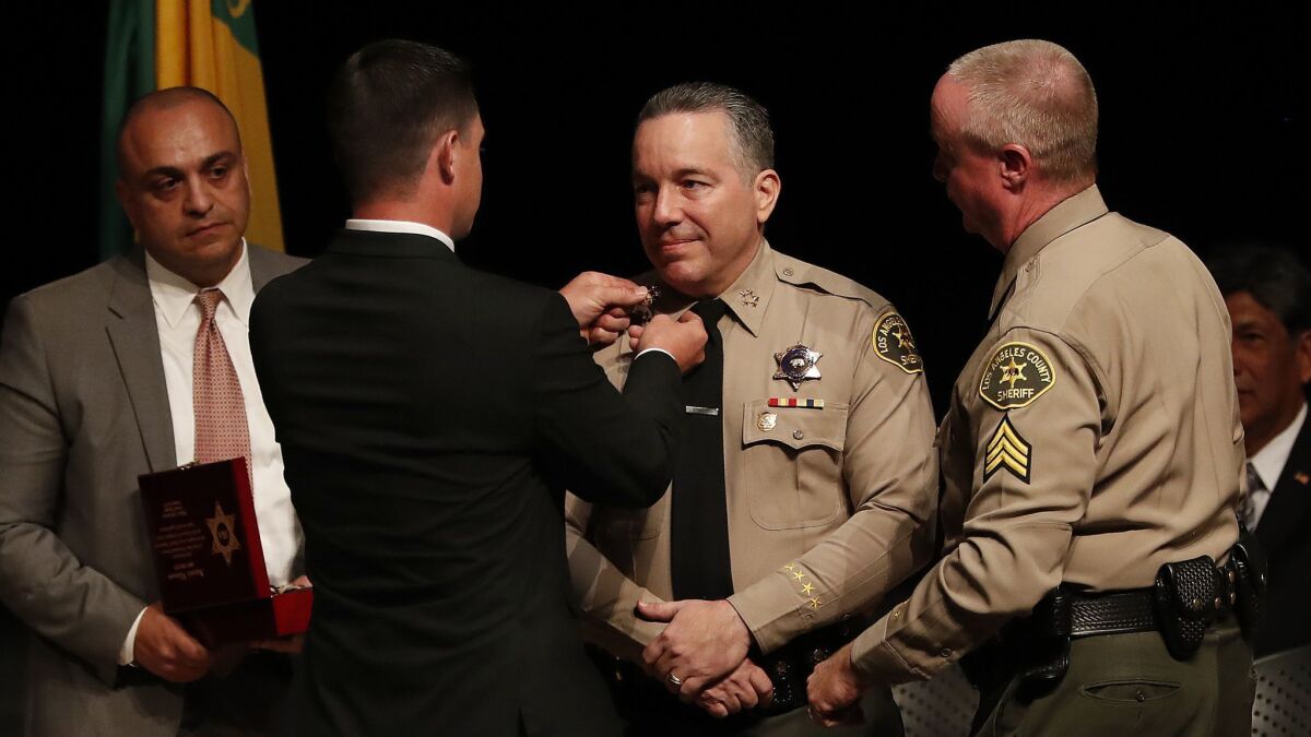 Jared Villanueva places a pin on the collar of his father, Alex Villanueva, at his swearing-in as Los Angeles County sheriff.