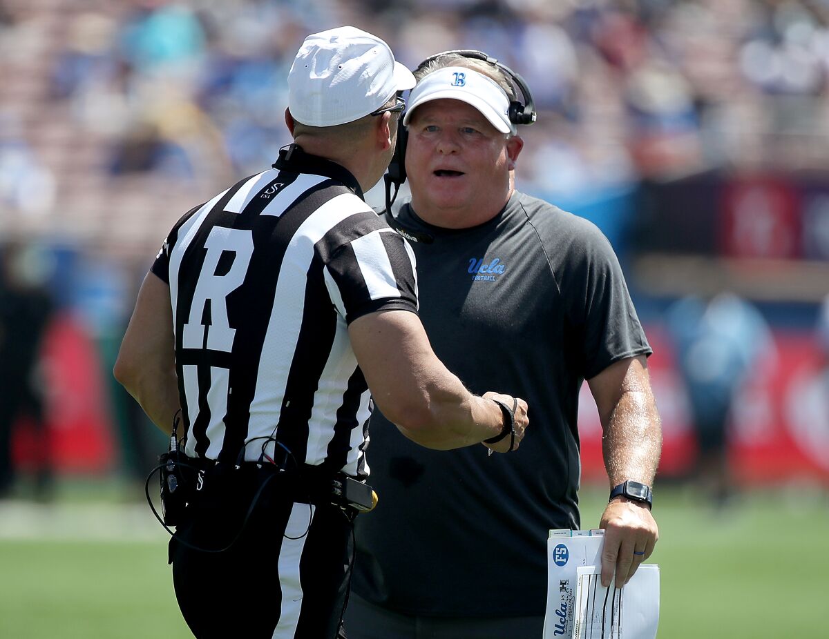 UCLA coach Chip Kelly talks with an official during a game against Hawaii