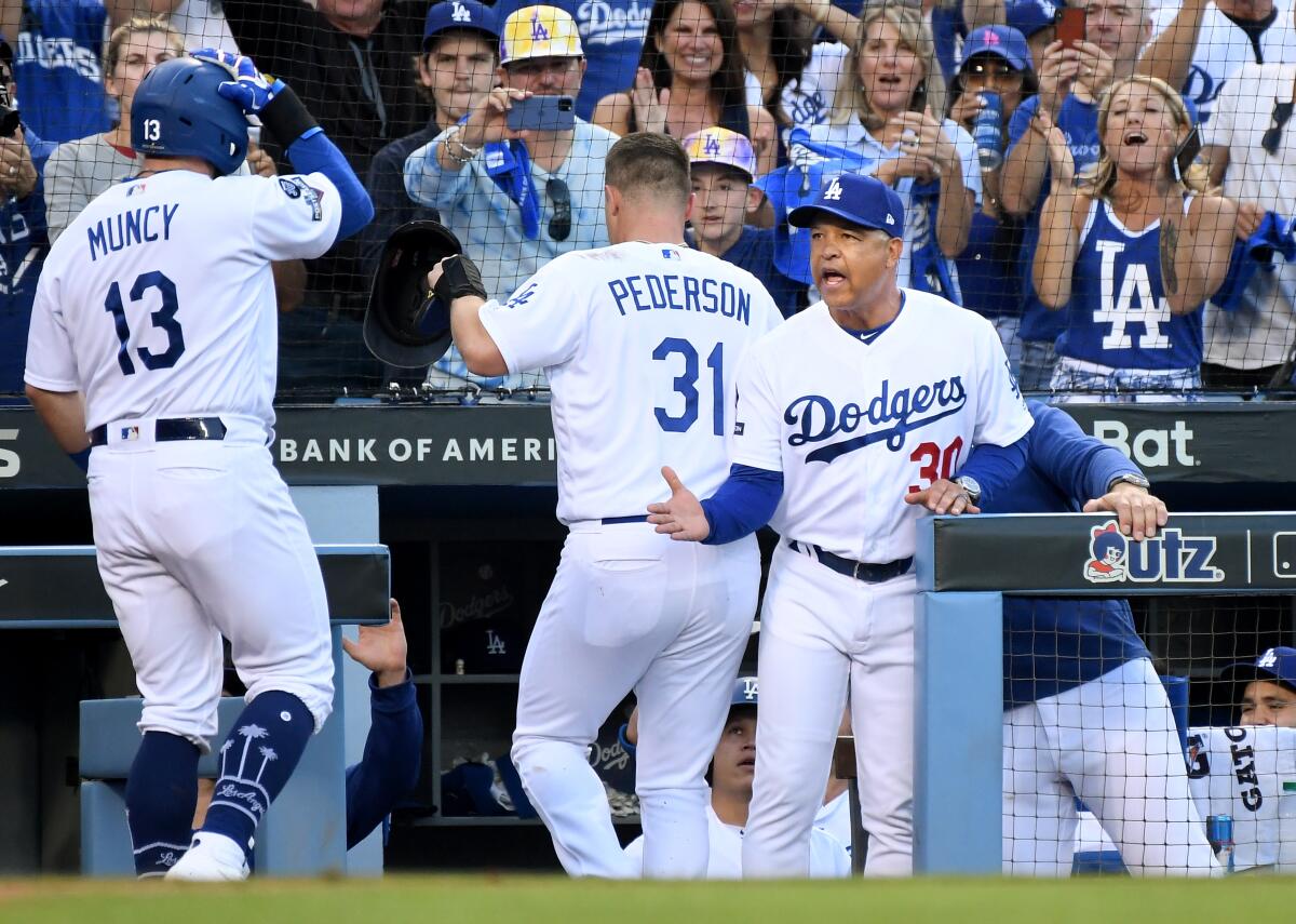 Dodgers manager Dave Roberts congratulates Max Muncy after his two-run home run against the Nationals in Game 5 of the NLDS at Dodger Stadium on Wednesday.