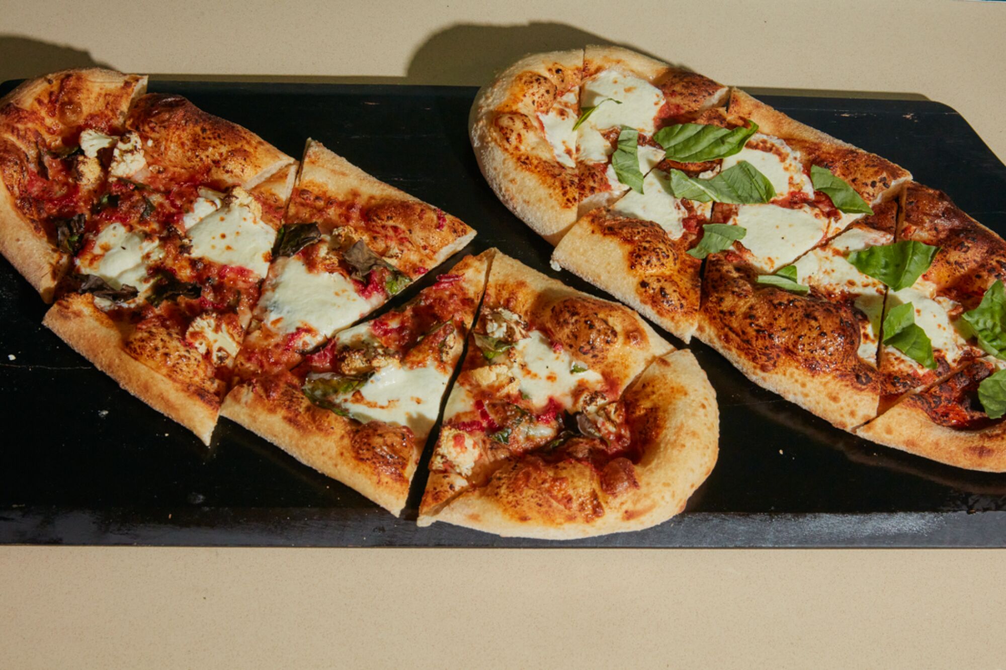 A  margherita and garden-inspired flatbread on a cutting board