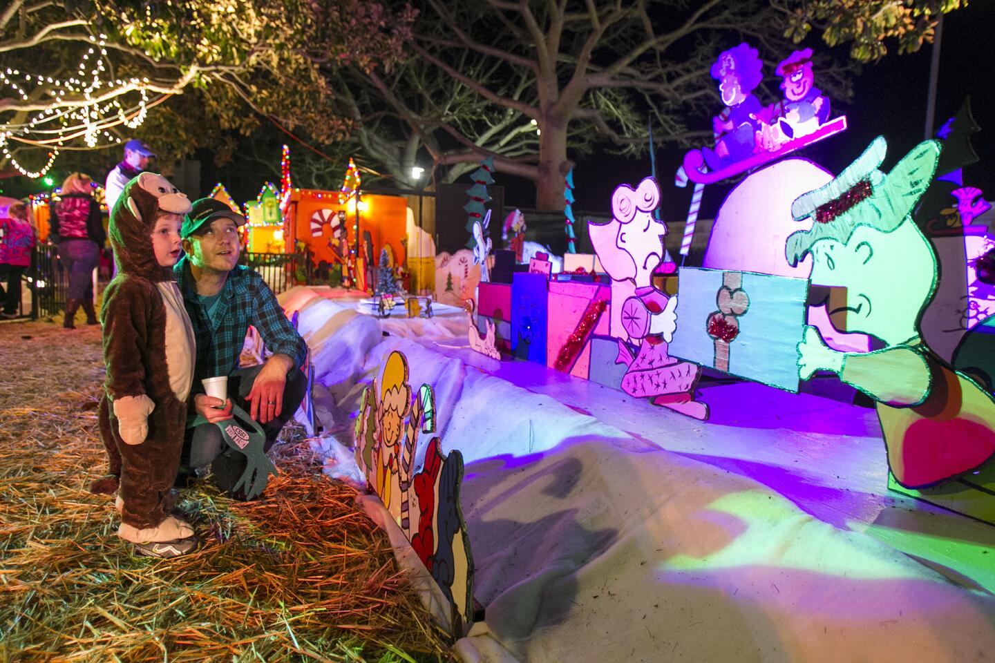 Josh Peevyhouse and his son Jamin, 3, look at part of the display during the official opening of the Snoopy House at Costa Mesa City Hall on Saturday, December 13.
