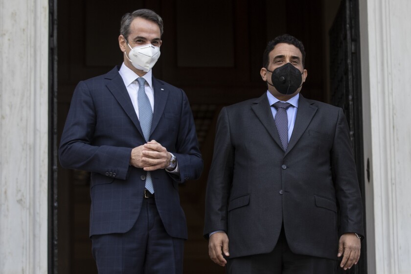 Greek Prime Minister Kyriakos Mitsotakis, left, and the head of the Presidential Council of Libya Mohamed al-Menfi, wear face masks to curb the spread of COVID-19 as they pose for photographers before their meeting, in Athens, on Wednesday, April 14, 2021.(AP Photo/Petros Giannakouris)