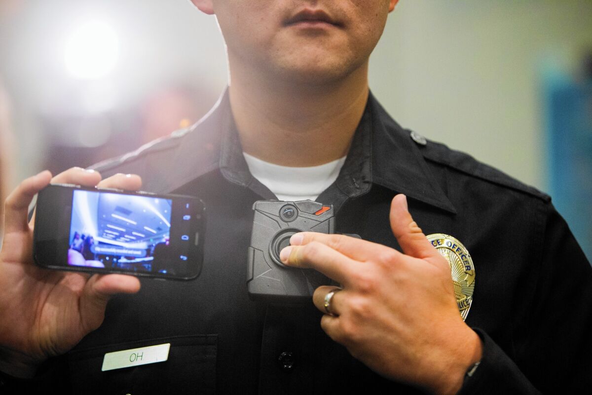An LAPD officer holds a live-view device, left, which works with the new Taser Axon on-body police cameras. The city plans to buy 6,140 cameras and 4,400 Tasers for its officers.