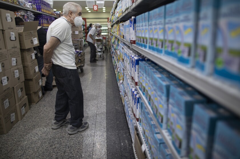A man looks at the prices of milk at a supermarket in Caracas, Venezuela, Friday, June 4, 2021. Two years ago Venezuela stopped restricting transactions in dollars, which has largely ended shortages but has meant many Venezuelans, who are paid in bolivars, can't afford what's on those shelves. ( AP Photo/Ariana Cubillos)