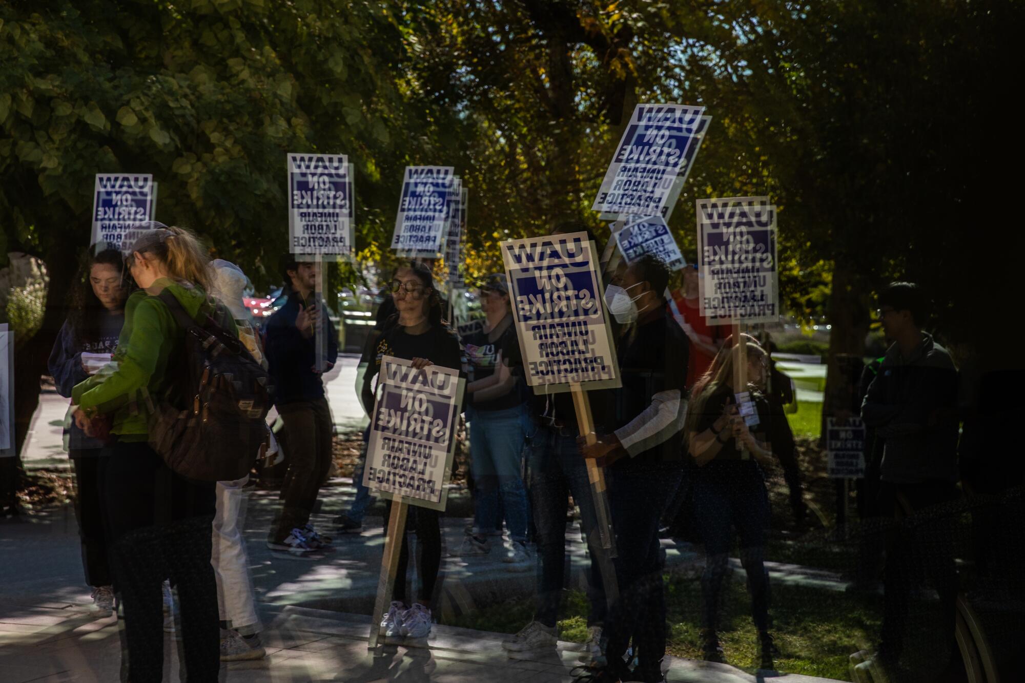 UC San Diego academic workers are seen reflected in a window while they strike.