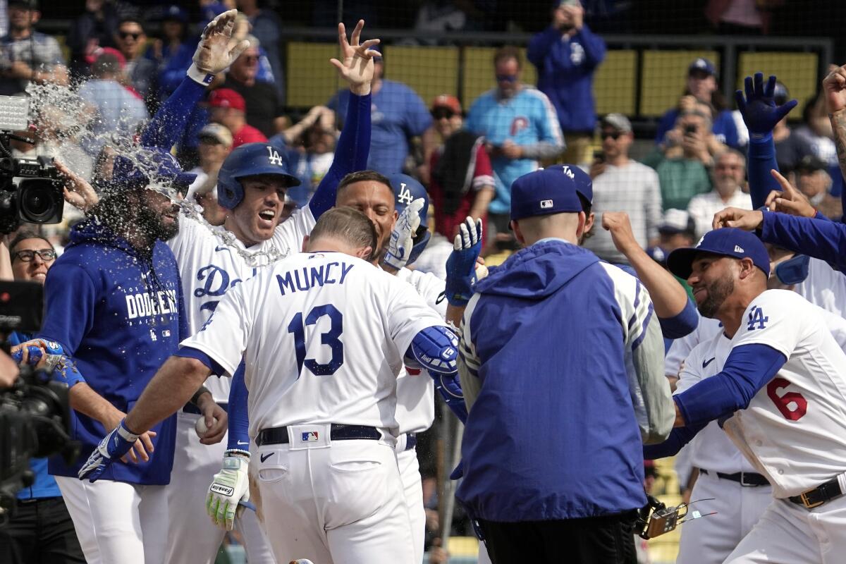 Dodgers' Max Muncy (13) is greeted by teammates after his ninth-inning grand slam beat the Phillies on Wednesday.