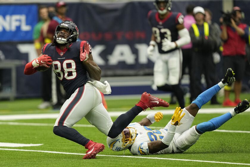 Houston Texans wide receiver John Metchie III (88) is tripped up by Los Angeles Chargers cornerback Asante Samuel Jr. (26) after a catch during the second half of an NFL football game Sunday, Oct. 2, 2022, in Houston. (AP Photo/David J. Phillip)