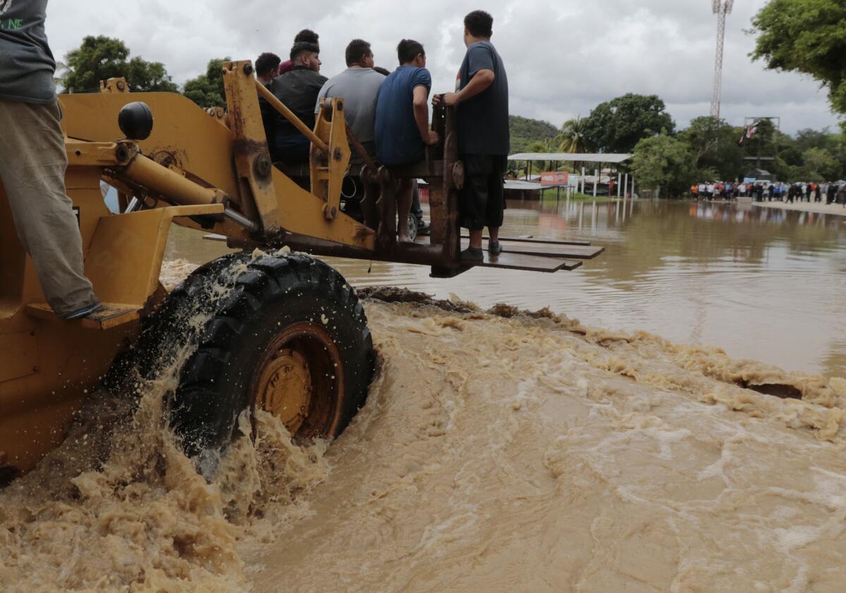 Un montacargas cruza a personas por una zona inundada tras el paso del huracán Iota en La Lima, Honduras