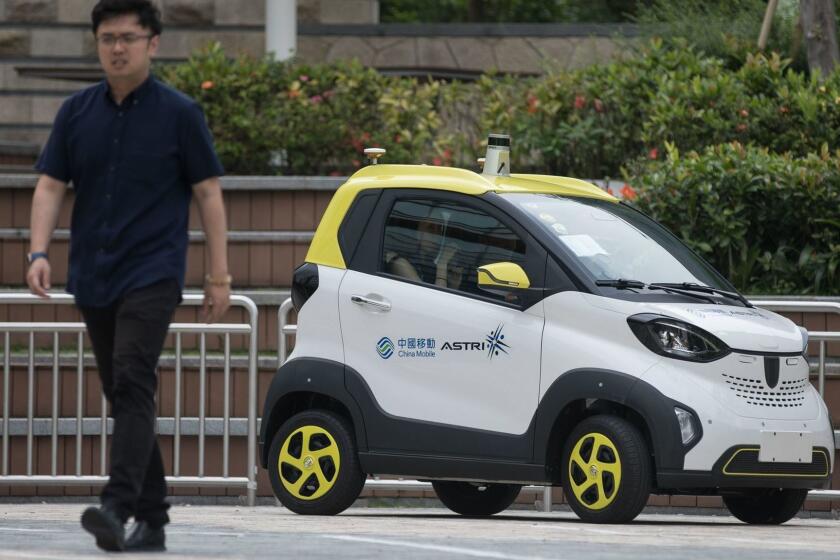 Mandatory Credit: Photo by JEROME FAVRE/EPA-EFE/REX (10209061a) A person walks past a China Mobile Hong Kong and Hong Kong Applied Science and Technology Research Institute (ASTRI) autonomous vehicle, which is equipped with 5G technology, at the Science Park in Hong Kong, China, 17 April 2019. The Hong Kong Open Lab of China Mobile Group's 5G Joint Innovation Center was moved from its former site to the Hong Kong Science Park where it can accommodate more advanced equipment, allowing local businesses to conduct R&D tests on 5G network applications. China Mobile 5G lab and driverless car test, Hong Kong - 17 Apr 2019 ** Usable by LA, CT and MoD ONLY **
