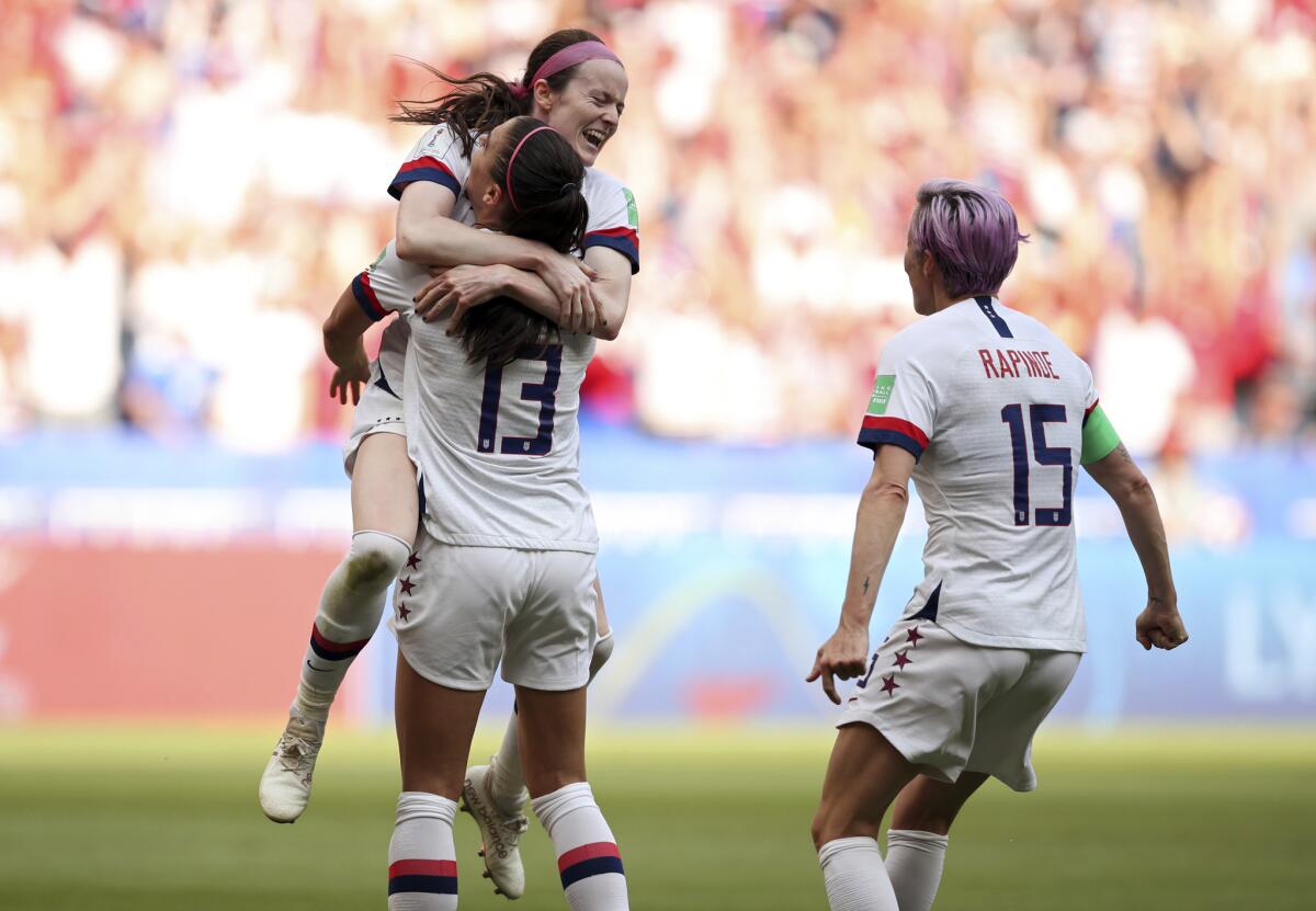 American midfielder Rose Lavelle leaps into the arms of Alex Morgan as they, along with Megan Rapinoe, celebrate a goal.