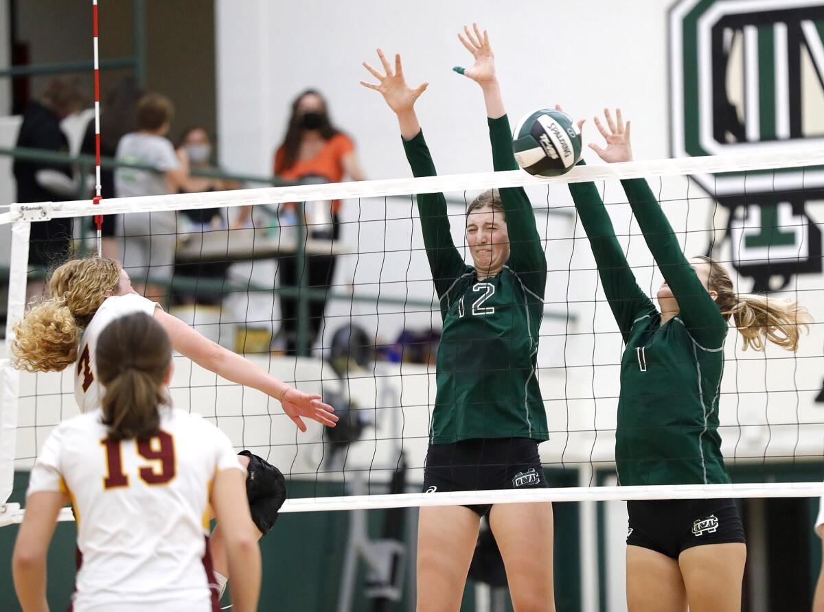 Costa Mesa's Lorelei Hobbis (12) and Hana Batlik go up for a block on Estancia's Ruby Uchytil on Thursday.