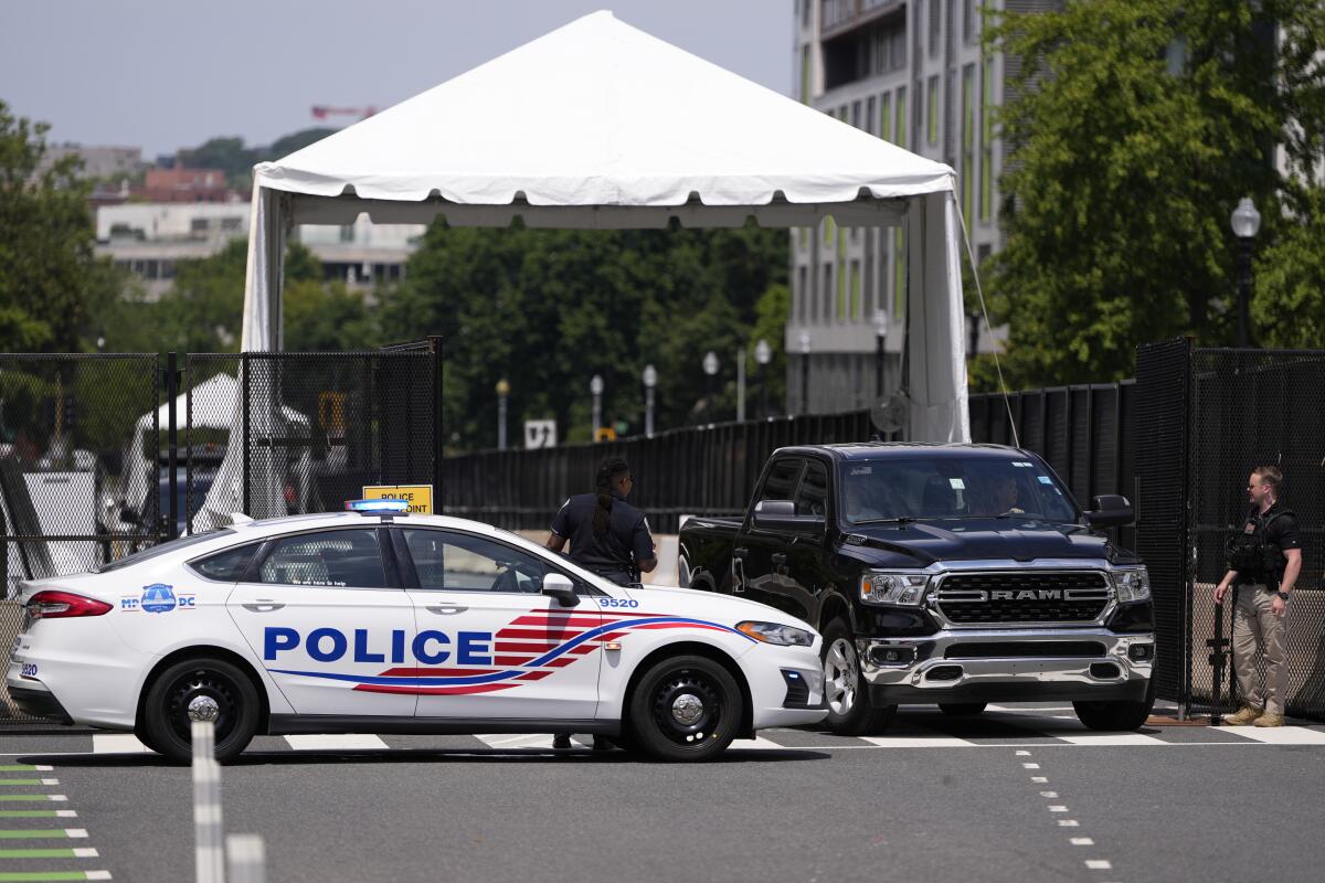 Vehicles and officers near an outdoor canopy outside a hotel 