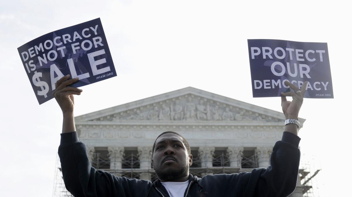 In a 5-4 vote, the U.S. Supreme Court on Wednesday struck down limits on the overall campaign contributions individual donors may make to candidates, political parties and political action committees. Above, Cornell Woolridge demonstrated in favor of campaign outside the Supreme Court on Oct. 8, 2013.