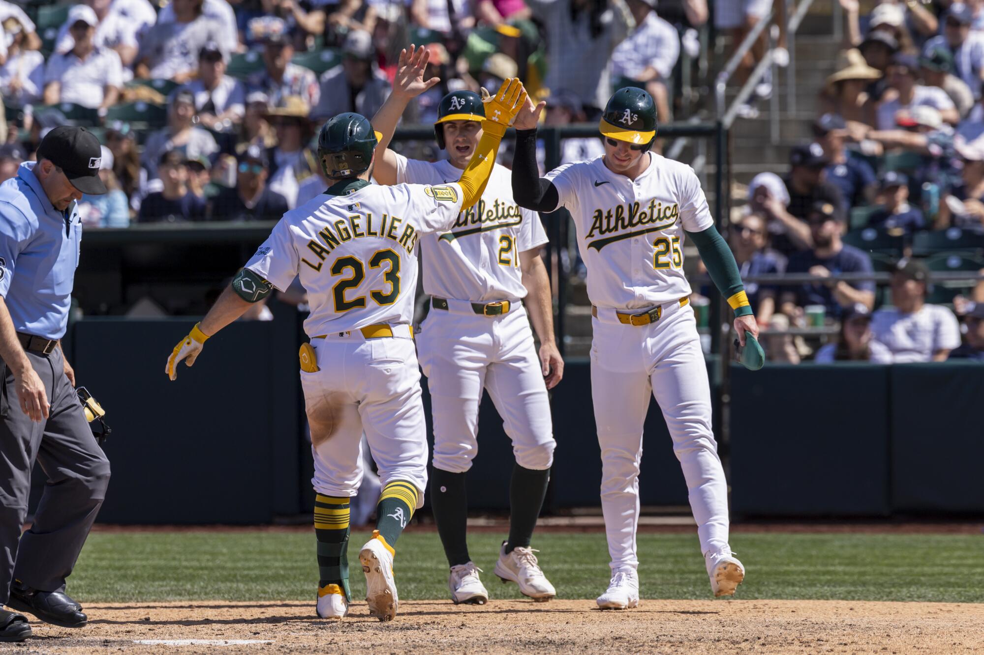 Shea Langeliers celebrates with Tyler Soderstrom and Brent Rooker after hitting a home run.