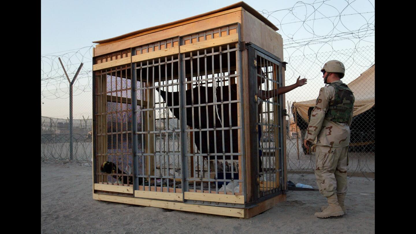A detainee in an outdoor solitary confinement cell talks with a military policeman at the Abu Ghraib prison on the outskirts of Baghdad in June 2004.