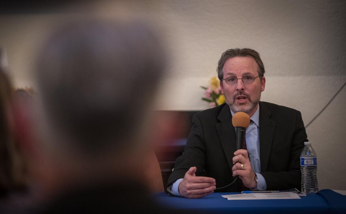 A man sitting at a table speaks into a microphone