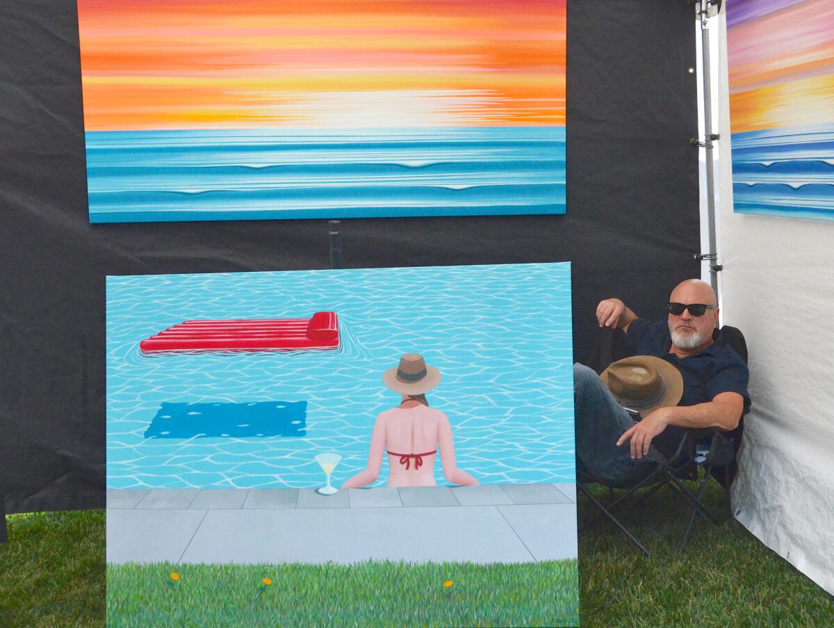 Artist Jerry Clovis relaxes behind his "Ocean Horizon" series of paintings display during Art in the Park.