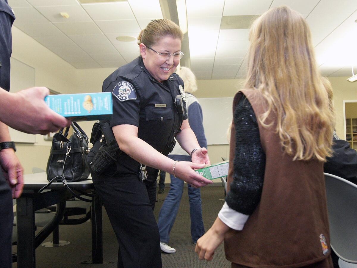 Glendale Police Lieutenant Lola Abrahamian is given a box of Girl Scout cookies by Juliana Rozanski, 9, of Glendale, at the Glendale Police Station on Monday, March 7, 2016. Dispatchers and officers chipped in $165 to help offset the loss of a Hello Kitty purse Juliana lost while selling Girl Scout cookies.