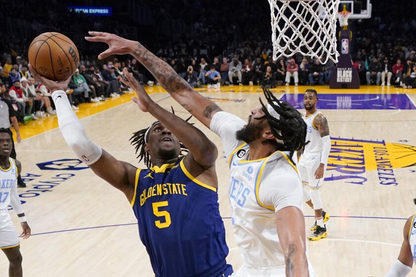 Golden State Warriors forward Kevon Looney, left, shoots as Los Angeles Lakers forward Anthony Davis defends during the first half of an NBA basketball game Thursday, Feb. 23, 2023, in Los Angeles. (AP Photo/Mark J. Terrill)