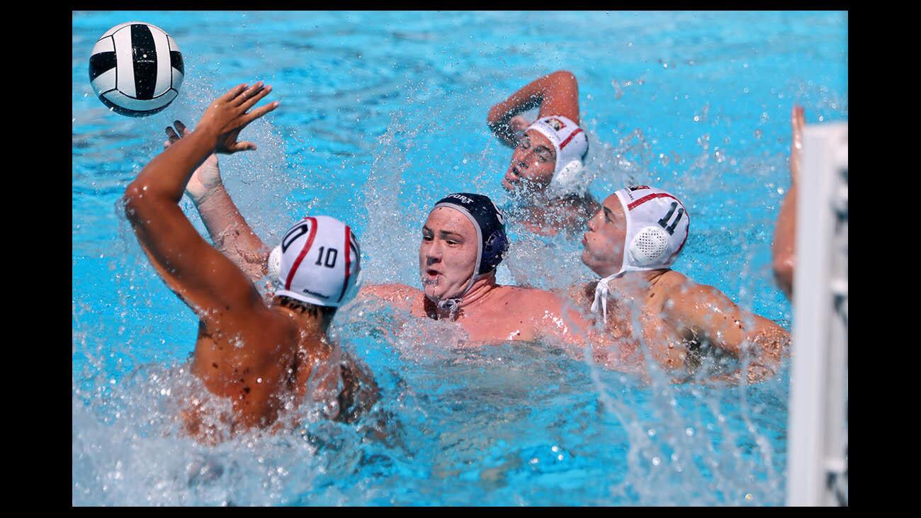 Newport Harbor High School boys water polo player #9 Ike Love gets rid of the ball under pressure by the Harvard-Westlake School defense in semifinal game of the 4th annual Elite 8 Water Polo Tournament, at Harvard Westlake School in Studio City on Saturday, Sept. 15, 2018.