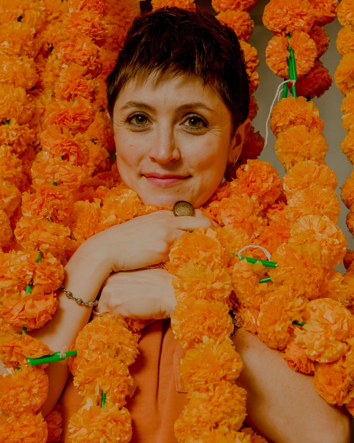 Tallie Medel poses for a portrait surrounded by orange flower blossoms.