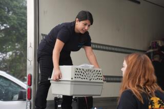San Diego Humane Society Executive Assistant of Operations Janina Chavarria takes an animal crate from Operations Project Manager Emily Scheerer to load into a truck headed to rescue partners in Tucson, Arizona, on Monday, Aug. 7, 2023.