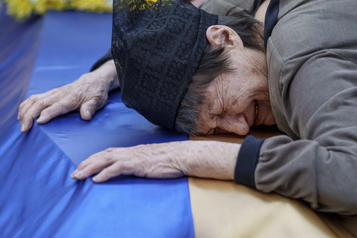 A mother cries over the coffin of her son killed in a Russian rocket attack.