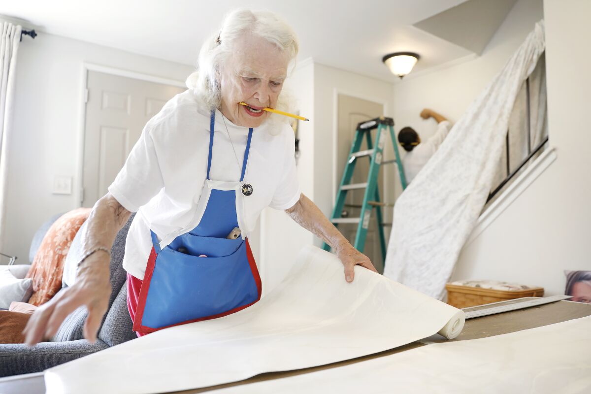 Reita Green rolls out wallpaper at a client's home in Newhall.