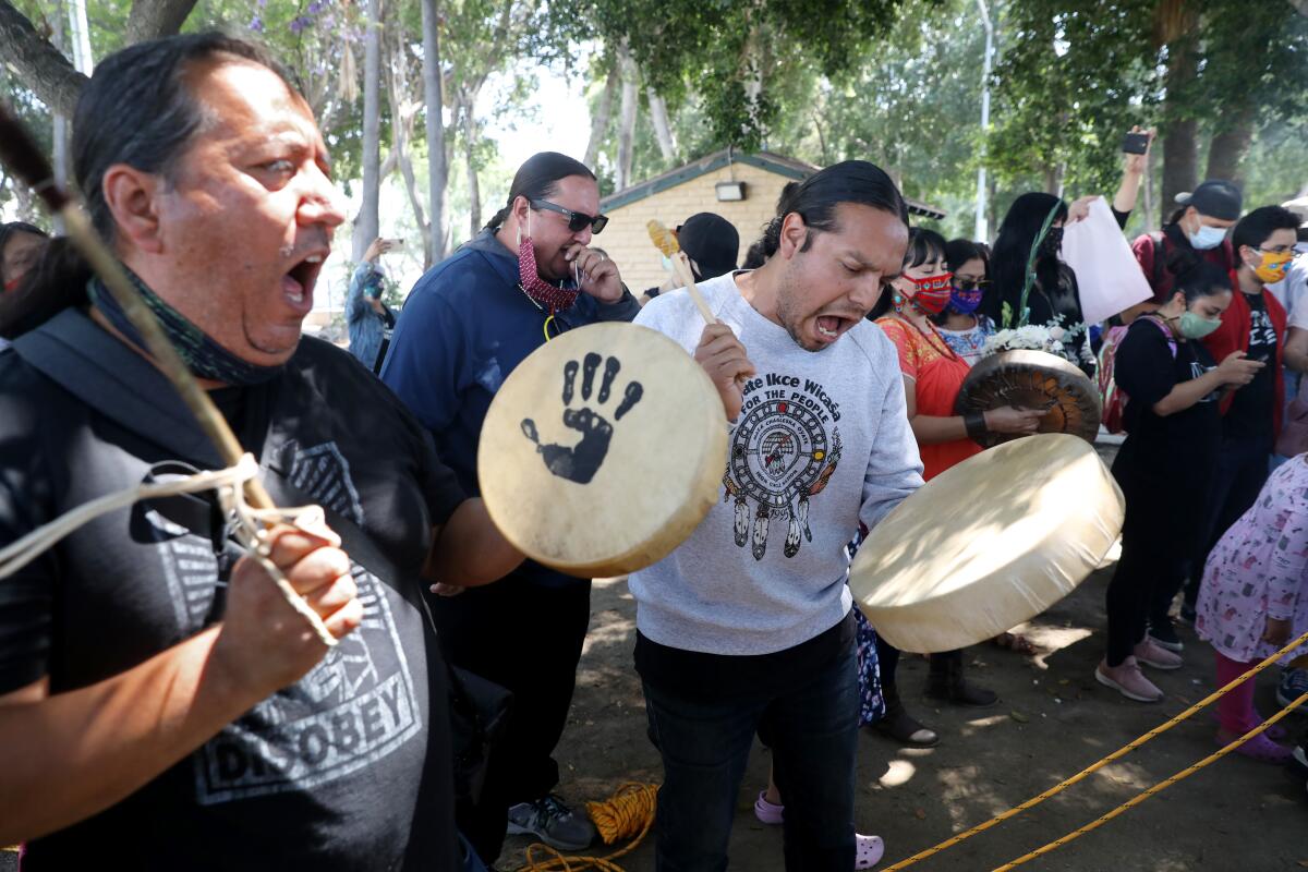Activists sing and play drums after toppling the statue of Father Junipero Serra in downtown L.A.