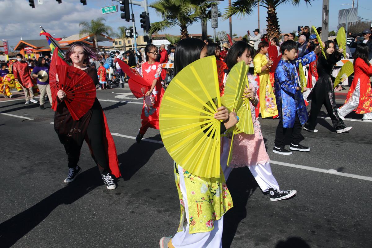 Youths carry colored fans as they take part in the 2023 Westminster Tet Parade.