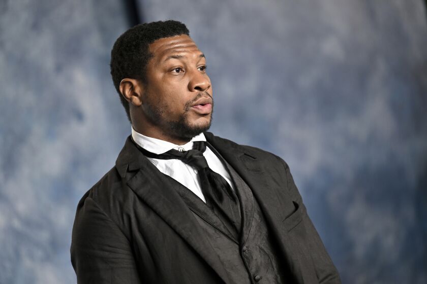 Jonathan Majors in a black suit and tie