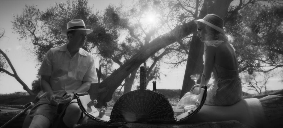 Gary Oldman and Amanda Seyfried sit in front of some sparse trees