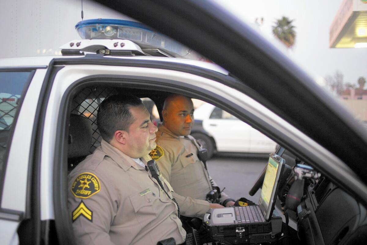 Deputy Ricardo Eguia, foreground, and Deputy Richard Raygoza sit in their car at the Compton Sheriff's Station on Feb. 13.